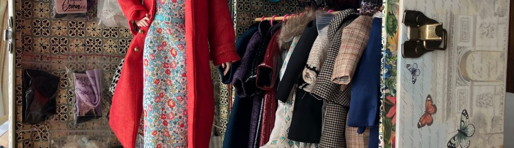 2002 Continental Holidays Silkstone Barbie redressed in Trench Setting coat and dress, in front of DIY wardrobe made by Deborah Cooke